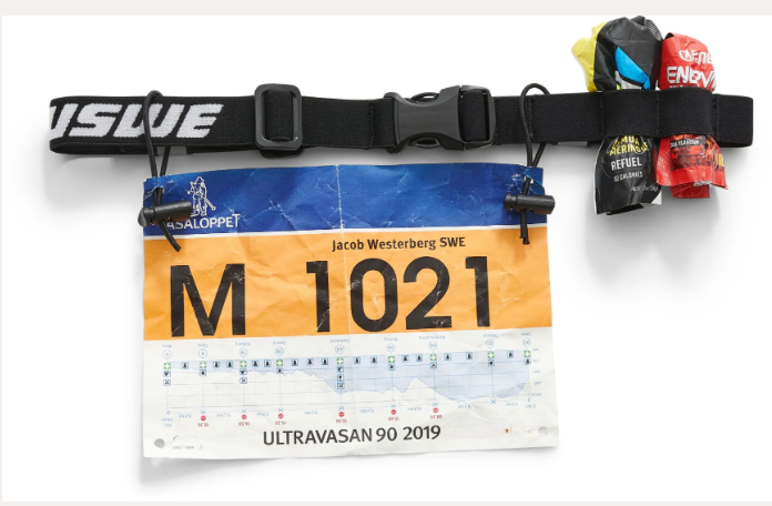USWE Race ID Belt shown in a screenshot, featuring adjustable straps and multiple storage pouches for outdoor racing and cycling.